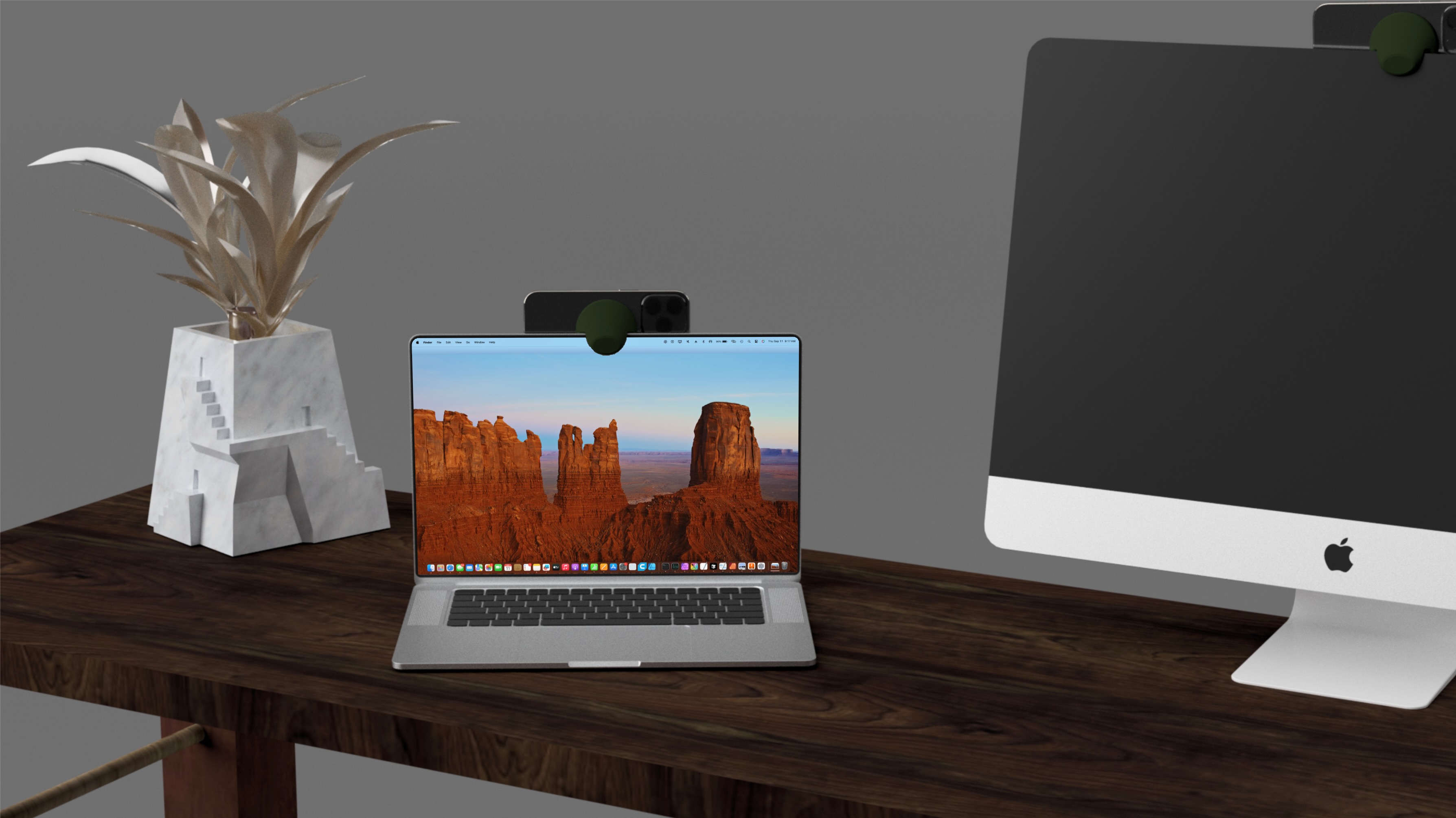 6. Modern desk workspace featuring MagMac Mount green silicone puck attaching iPhones to MacBook Pro and iMac for Continuity Camera integration, displaying desert canyon wallpaper on laptop, plant in marble vase, wooden surface, minimalist design language, MFi-certified MagSafe compatibility, universal Mac mounting, enhancing video quality with superior iPhone cameras over built-in webcams, optimized for seamless Apple ecosystem and professional video calls.